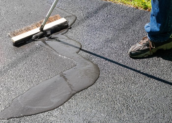Spreading asphalt resealer onto driveway for maintenance